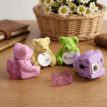 Teddy Bear Eraser & SharpenerCrafty CuddleFour bear - shaped sharpeners in pink, yellow, green, and purple on a wooden surface with a basket of flowers in the background.Teddy Eraser Sharpener-11