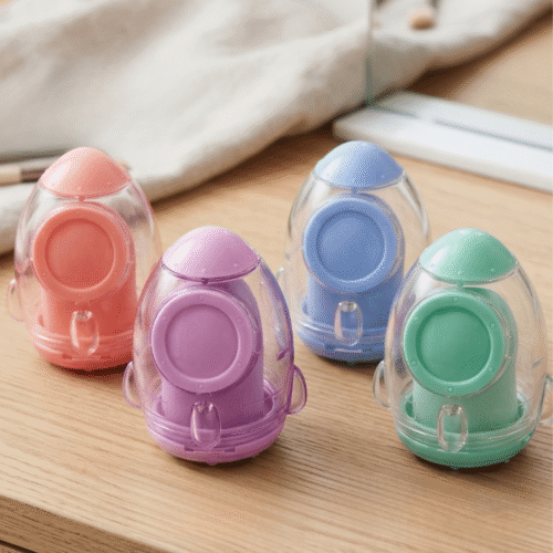 Four colorful plastic sharpeners on a wooden surface