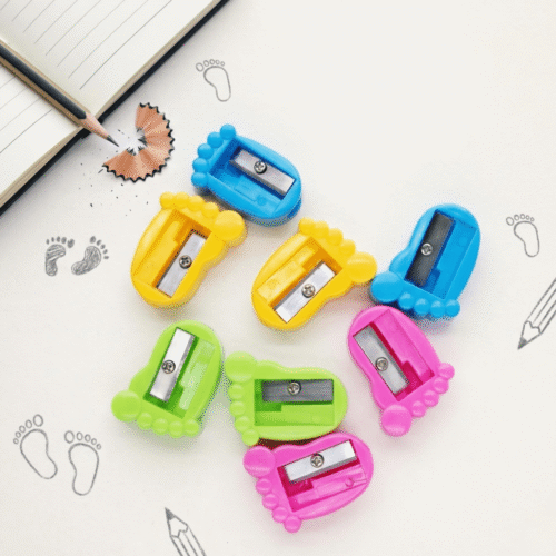 Colorful pencil sharpeners on a white surface with footprints and a pencil.