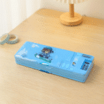 Smart Pencil Box with CalculatorPencil BoxCrafty CuddleBlue pencil case with cartoon design on a wooden surfaceSky Bluepencilbox kidsstationery multifunctionpencilbox cartoonpencilcase schoolstationery kidsstudyessentials stationeryforkids cutestationery backtoschool studentstationery