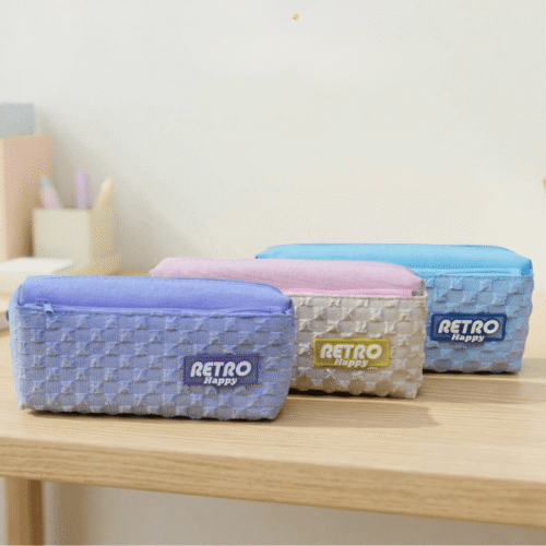 Three retro-style pencil cases on a wooden surface with a light background