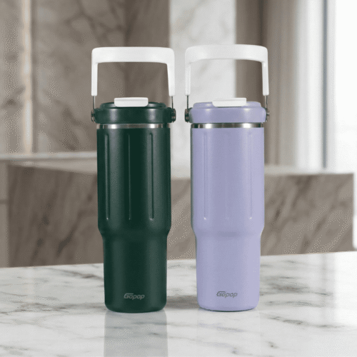 Two insulated travel mugs, one green and one purple, on a marble surface with a neutral background.