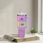 Pink Stanley tumbler with a straw on a wooden surface with a plant in the background