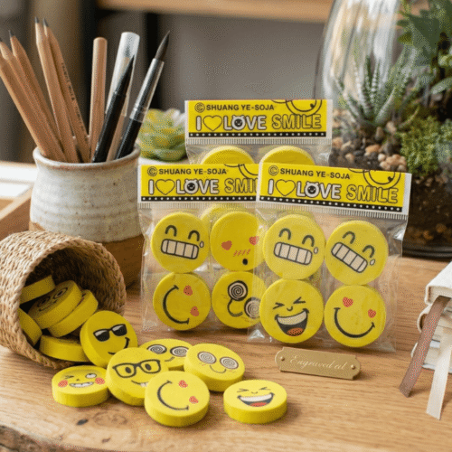 Packaged yellow smiley face erasers with 'I ❤️ Love Smile' text on a wooden surface.