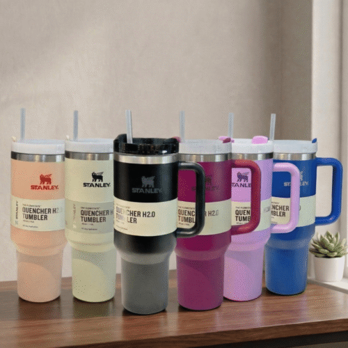 Set of Stanley tumblers in various colors on a wooden surface with a neutral background.