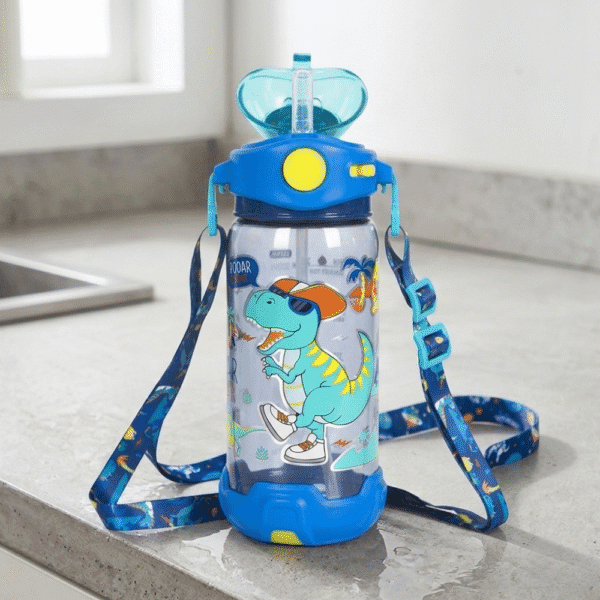 Children's water bottle with dinosaur design and blue strap on a kitchen counter