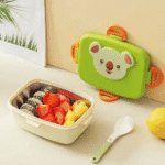 Green bento box with koala design, containing food, on a light surface.