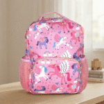 Pink backpack with unicorn pattern on a wooden surface