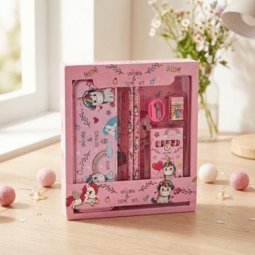 Pink stationery set with unicorn design in a box on a wooden surface.