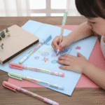 Child drawing with colorful pens on a notebook