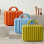 Three colorful makeup cases (orange, blue, yellow) on a neutral background