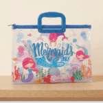 Transparent Kids Document BagKids BagsCrafty CuddleClear pouch with mermaid design and blue handle on a beige backgroundMermaidKidsFileBag CartoonStationery KidsOrganizer SchoolSupplies CuteStationery KidsDocumentBag StationeryLovers KidsSchoolEssentials A4FileBag TransparentBag