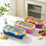 Colorful children's lunch boxes on a marble surface with snacks around