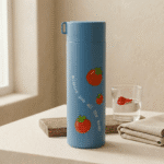 Cute Fruit Print Glass Water BottleCartoon Kids Water BottleCrafty CuddleBlue thermos bottle with tomato designs and text on a table with a glass of water and folded towel.BlueWaterBottle CuteBottle FruitPrint KidsBottle GlassBottle SchoolEssentials KawaiiProducts DailyUse BackToSchool HydrationStyle