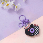 Cute Camera Shape Projector KeychainKeychainsCrafty CuddleDinosaur - themed camera keychain with a bell on a pastel background with flowersBlackCuteKeychain KawaiiAccessories KidsAccessories ReturnGiftIdeas CartoonKeychain MiniCamera BagCharm StationeryLove GiftForKids TrendingNow