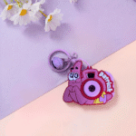 Pink cartoon snail camera keychain with 'Patrick' on a two-tone pink and purple background.
