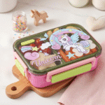Cartoon Kids Bento Lunch BoxStainless Steel Lunch BoxCrafty CuddleColorful unicorn - themed lunch box on a wooden board with small decorative items in the background.UnicornKidsLunchBox LunchBox BentoBox SchoolLunch KidsLunch LunchBoxIdeas BackToSchool CuteLunchBox KidsEssentials LunchTime