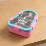 Kids 2 Compartment Lunch Box with Spoon & ForkStainless Steel Lunch BoxCrafty CuddlePink and blue lunch box with 'enjoy time' text on a wooden surfacepinkKidsLunchBox BentoBox LunchBox SchoolLunch KidsEssentials LunchBoxIdeas BackToSchool LeakproofLunchBox KidsLunch TiffinBox