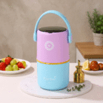 2 Layer Insulated Lunch Box with HandleStainless Steel Lunch BoxCrafty CuddleColorful lunch box on a table with fruits and a plant in the backgroundPurpleLunchBox TiffinBox InsulatedLunchBox LeakproofLunchBox OfficeEssentials KidsLunchBox MealPrepIndia FoodStorage LunchOnTheGo KitchenEssentials