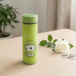 Cartoon Print Glass Water BottleCartoon Kids Water BottleCrafty CuddleGreen thermos with a cartoon bear design on a wooden surface with a white rose and lavender.GreenWaterBottle CuteBottle KidsBottle CartoonBottle GlassBottle SchoolEssentials BackToSchool KawaiiStyle HydrationGoals CuteAccessories