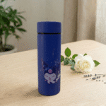 Cartoon Print Glass Water BottleCartoon Kids Water BottleCrafty CuddleBlue thermos bottle with cat design on a wooden table with a white rose and green leaves.Navy BlueWaterBottle CuteBottle KidsBottle CartoonBottle GlassBottle SchoolEssentials BackToSchool KawaiiStyle HydrationGoals CuteAccessories