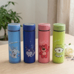 Four colorful thermos bottles with cartoon designs on a wooden surface.
