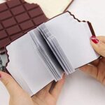 Hand holding a small notebook with white pages against a chocolate bar background