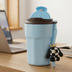 Light blue travel mug with a brown lid on a desk next to a laptop