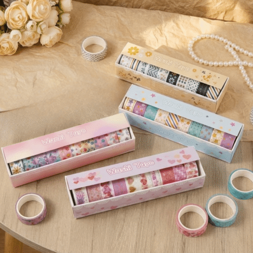 Set of colorful washi tape rolls in decorative boxes on a wooden surface with flowers and jewelry.